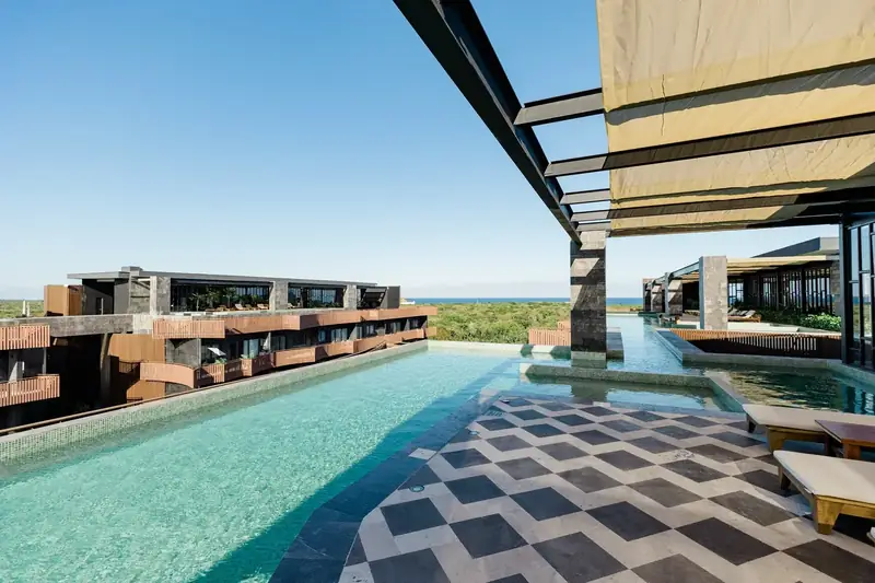 Long rooftop pool facing the jungle, with the sea on the horizon